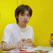 a man in a white shirt is eating a pizza with a yellow background