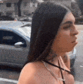 a woman with long hair and a tattoo on her neck is standing in front of a car