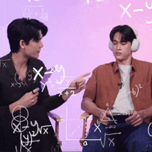 two men are sitting in front of a purple board with mathematical equations written on it