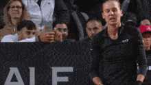 a woman wearing a black ea7 shirt holds a tennis racket
