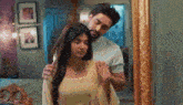 a man is standing next to a woman in front of a mirror .