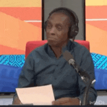 a man wearing headphones is sitting in front of a microphone .