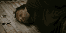 a man in a black shirt is laying on the ground with his eyes closed