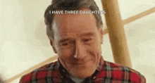 a man in a plaid shirt is smiling with the words `` i have three daughters '' above him .