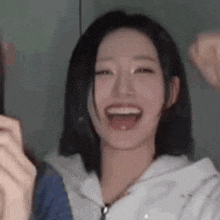a close up of a woman laughing with her mouth open and a fist in the air .