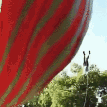 a red and green striped hot air balloon is flying in the sky