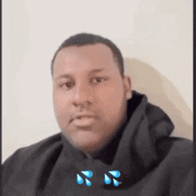 a man wearing a black hoodie has tears on his face