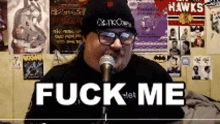 a man is singing into a microphone with the words " fuck me " on the screen
