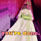 a woman in a green coat is standing on a stage with the words " you 're done " written on the bottom