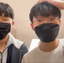 two boys wearing face masks and glasses standing next to each other