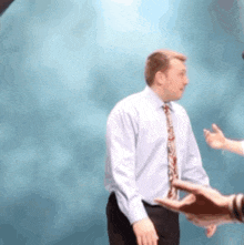 a man in a tie is shaking hands with another man .