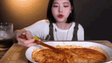 a woman is eating a plate of food with chopsticks ..