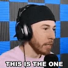 a man wearing headphones and a beanie is talking into a microphone .