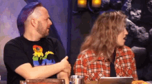 a man with purple hair is sitting next to a woman in a plaid shirt
