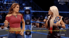 two women are in a wrestling ring and one of them is talking into a microphone
