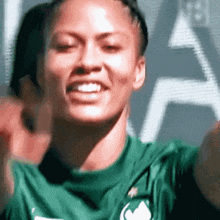 a woman in a green shirt is taking a selfie with her hands in the air .
