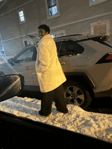 a man in a white coat stands in front of a car