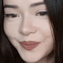 a close up of a woman 's face with long black hair and red lipstick .