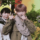 a boy wearing a yellow hat is giving a thumbs up next to a girl wearing a scarf