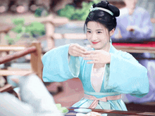 a woman in a blue dress with a flower in her hair is smiling