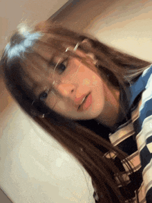 a girl wearing glasses and a plaid shirt looks down at the camera