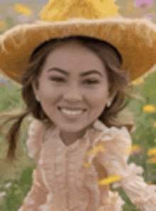 a woman wearing a straw hat and a pink dress is smiling in a field of flowers .