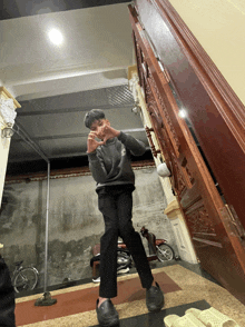 a person standing in front of a wooden staircase wearing a black sweater that says ' lg ' on it
