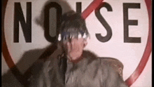 a man in a military uniform is standing in front of a no noise sign .