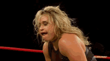 a woman is kneeling down in a wrestling ring and making a face .