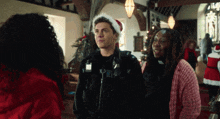a police officer wearing a santa hat is standing next to two women