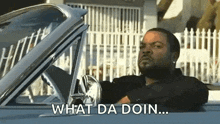 ice cube is sitting in the driver 's seat of a car and saying what da doin .