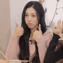 a girl with long black hair is giving a thumbs up sign