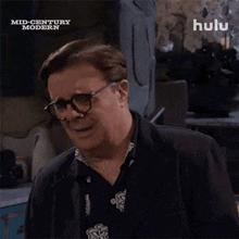 a man wearing glasses and a suit says curses in front of a hulu logo