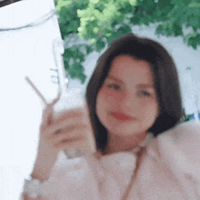 a woman is holding a straw in her hand and drinking from a glass .