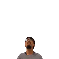 a man with glasses looks up at a green cross above his head