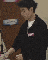 a young man is standing in front of a door with a vacant sign hanging on it .