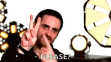 a man is making a peace sign with his finger in his nose and asking for a please .