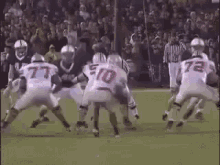 a group of football players are playing a game on a field with a referee .