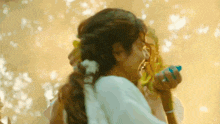 a girl with a flower in her hair is blowing soap bubbles outdoors