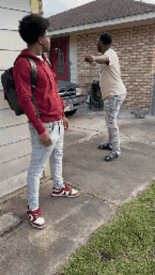 two men standing on a sidewalk in front of a house