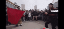 a man holding a red cloth in front of a crowd with the number 38,579,994 on the screen