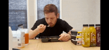 a man is sitting at a table eating a meal from a container that says factor on it