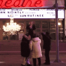 a group of people standing in front of a theatre