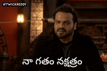 a man with long hair and a beard is sitting in front of a sign that says ' 7wickreddy ' on it