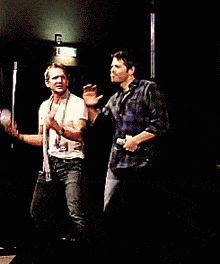 two men are dancing on a stage in front of a exit sign