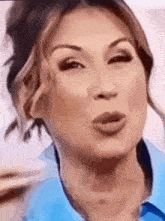 a woman wearing a blue shirt is blowing a kiss .