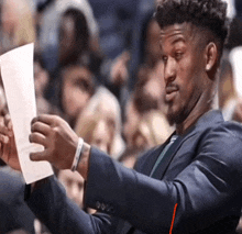 a man in a suit is holding a piece of paper in his hand