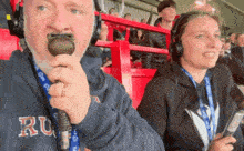 a man is holding a microphone while wearing a lanyard that says ru