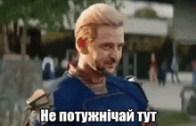 a man in a superhero costume is standing in front of a building and talking in a foreign language .