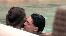 a man and a woman are kissing in a swimming pool